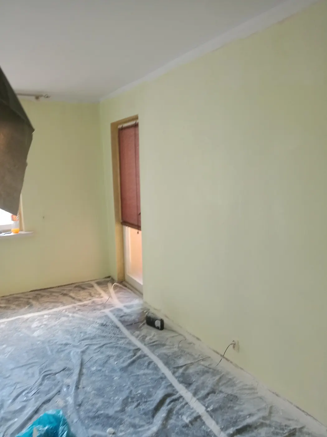 Pomieszczenie po malowaniu ścian na jasną zieleń, podłoga nadal zabezpieczona folią